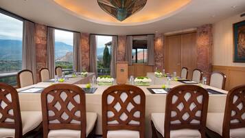 Comedor con vista panorámica a las montañas, sillas de madera con diseños elaborados en el respaldo y una lámpara de araña moderna.
