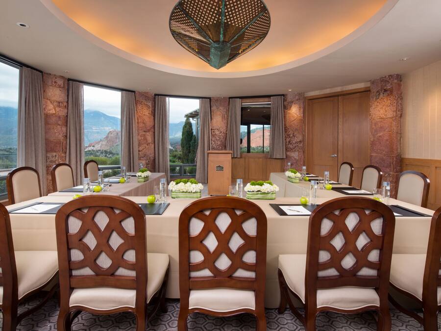 Comedor con vista panorámica a las montañas, sillas de madera con diseños elaborados en el respaldo y una lámpara de araña moderna.