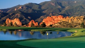 A golf course with a pond, green hills, and red rock formations in the background. - Garden of the Gods Resort and Club (Colorado Springs)
