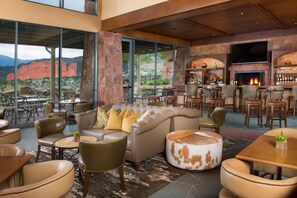 Eine großzügige Lounge mit Ledersofas, Holztischen und einer Bar mit Kamin.