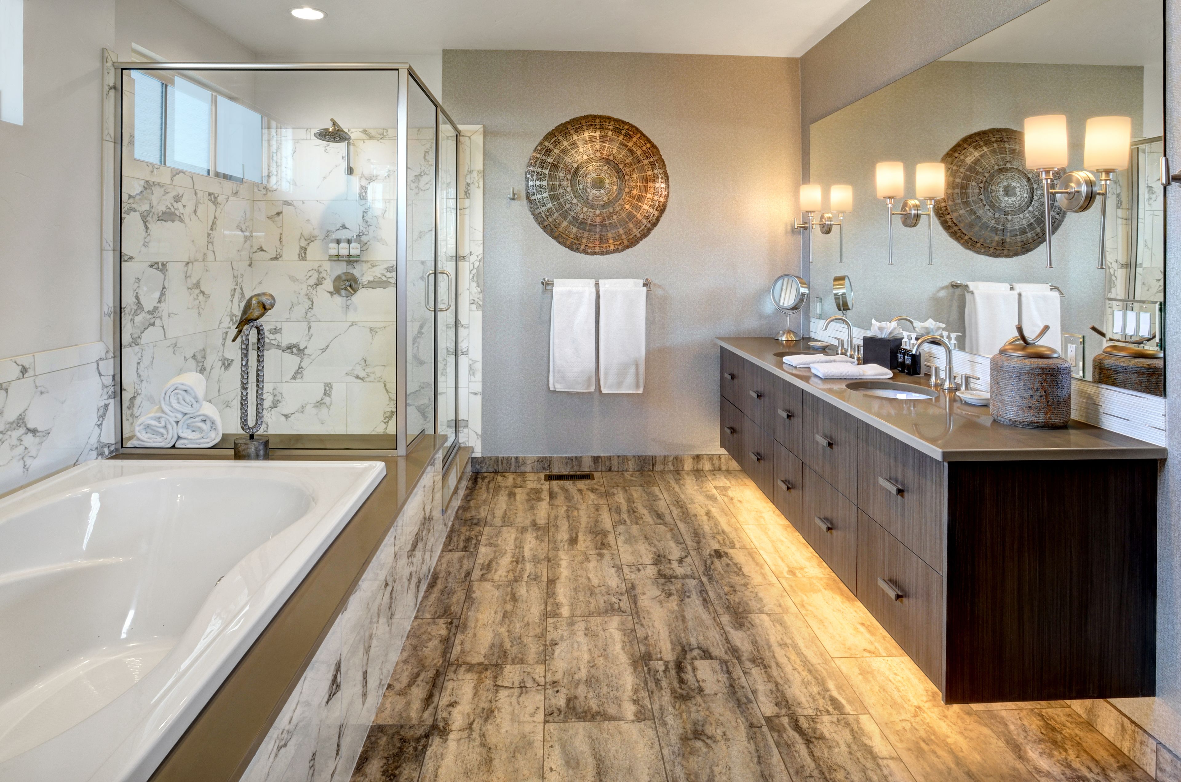 A modern bathroom with a glass-enclosed shower, a large bathtub, and a vanity with a mirror and sink.