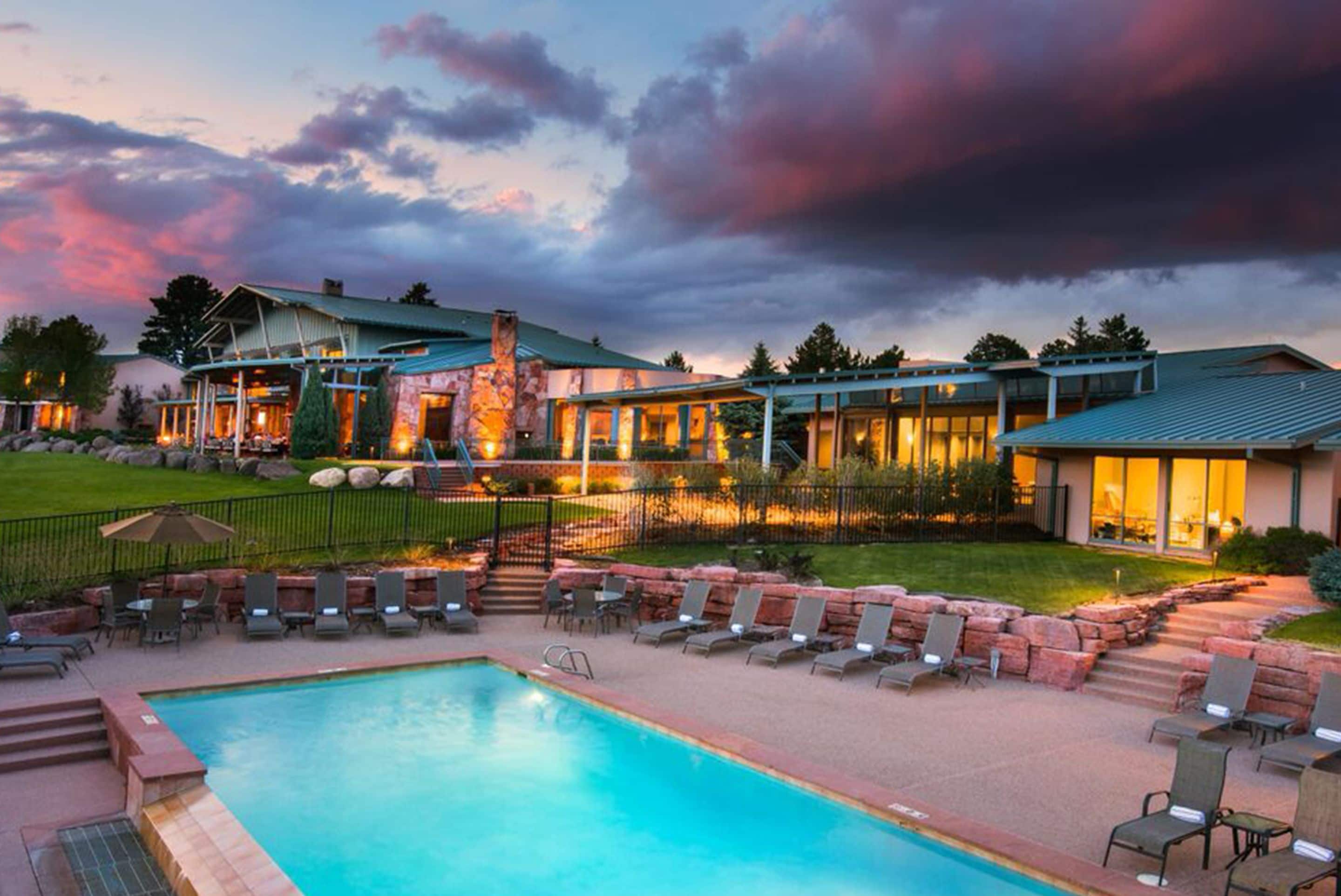 A resort with a swimming pool, lounge chairs, and a building with a stone facade.