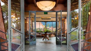 A spacious room with a large table and chairs, a potted plant, and a view of a mountainous landscape through glass doors. - Garden of the Gods Resort and Club (Colorado Springs)
