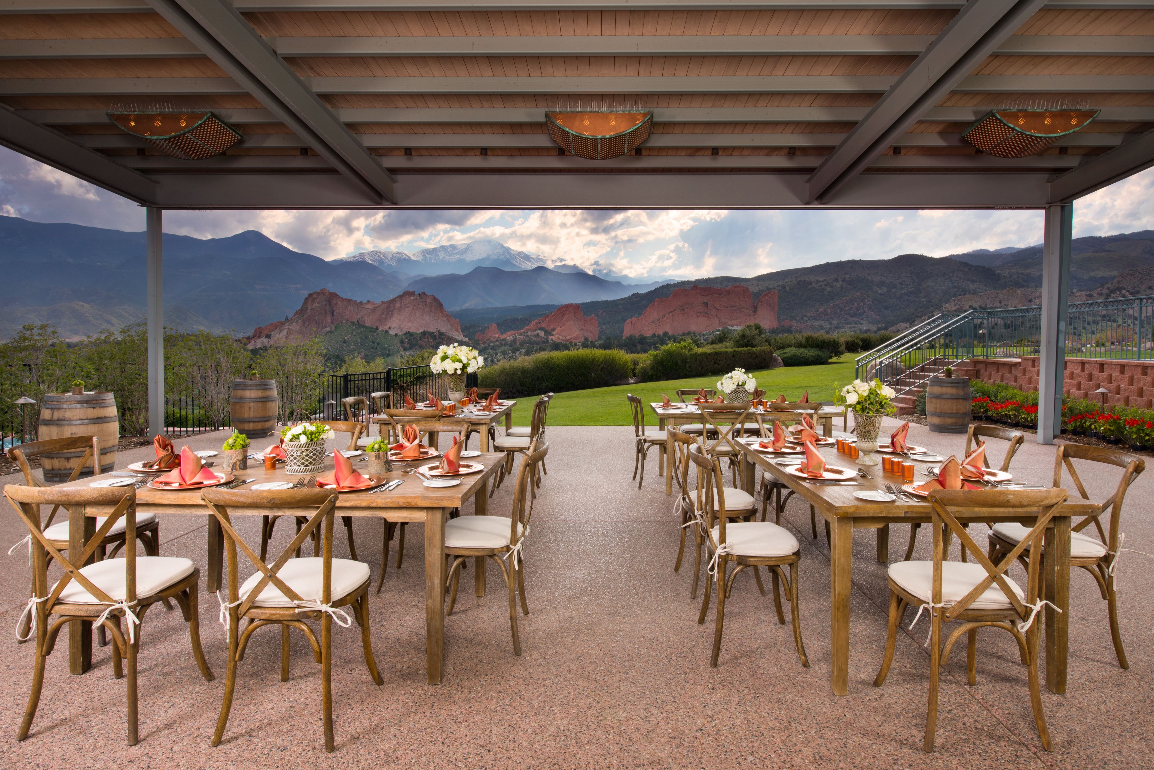 An outdoor dining area with tables and chairs, set against a backdrop of mountains and a clear sky.