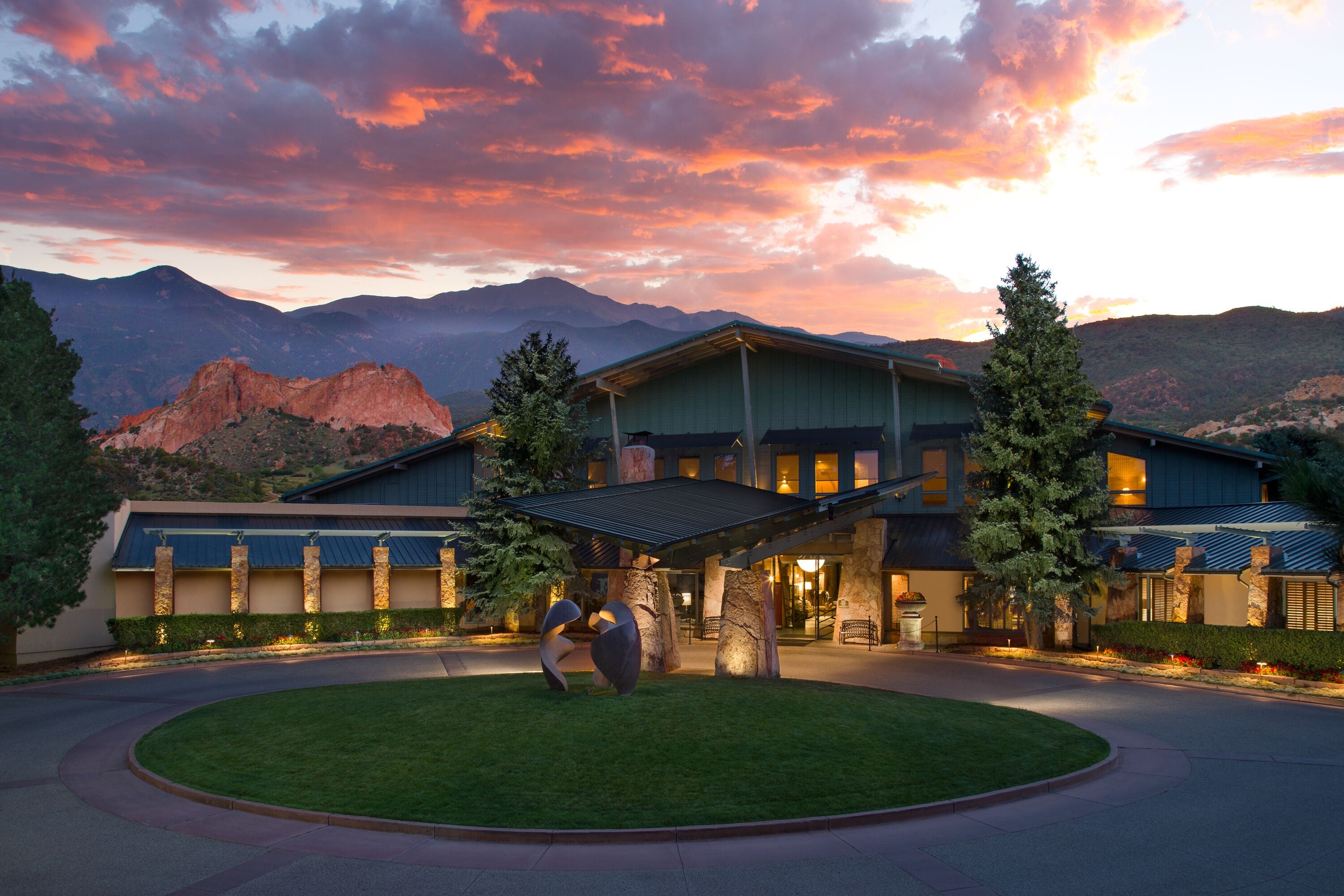 A hotel with a large, open lobby, a covered outdoor area, and a view of mountains in the background.