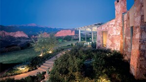 A modern house with a stone facade, a covered patio, and a view of red rock formations. - Garden of the Gods Resort and Club (Colorado Springs)