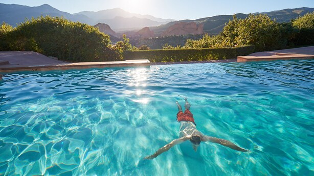 A swimming pool with clear water and a person swimming. - Garden of the Gods Resort and Club (Colorado Springs)