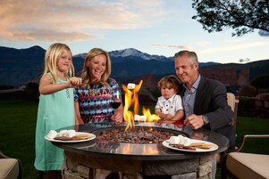 Una familia alrededor de un brasero, con montañas al fondo.