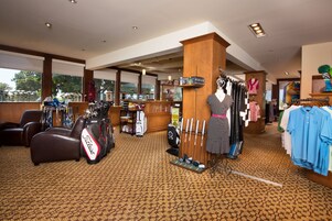 Una tienda de golf con bolsas, palos y una exhibición de zapatos para golf.