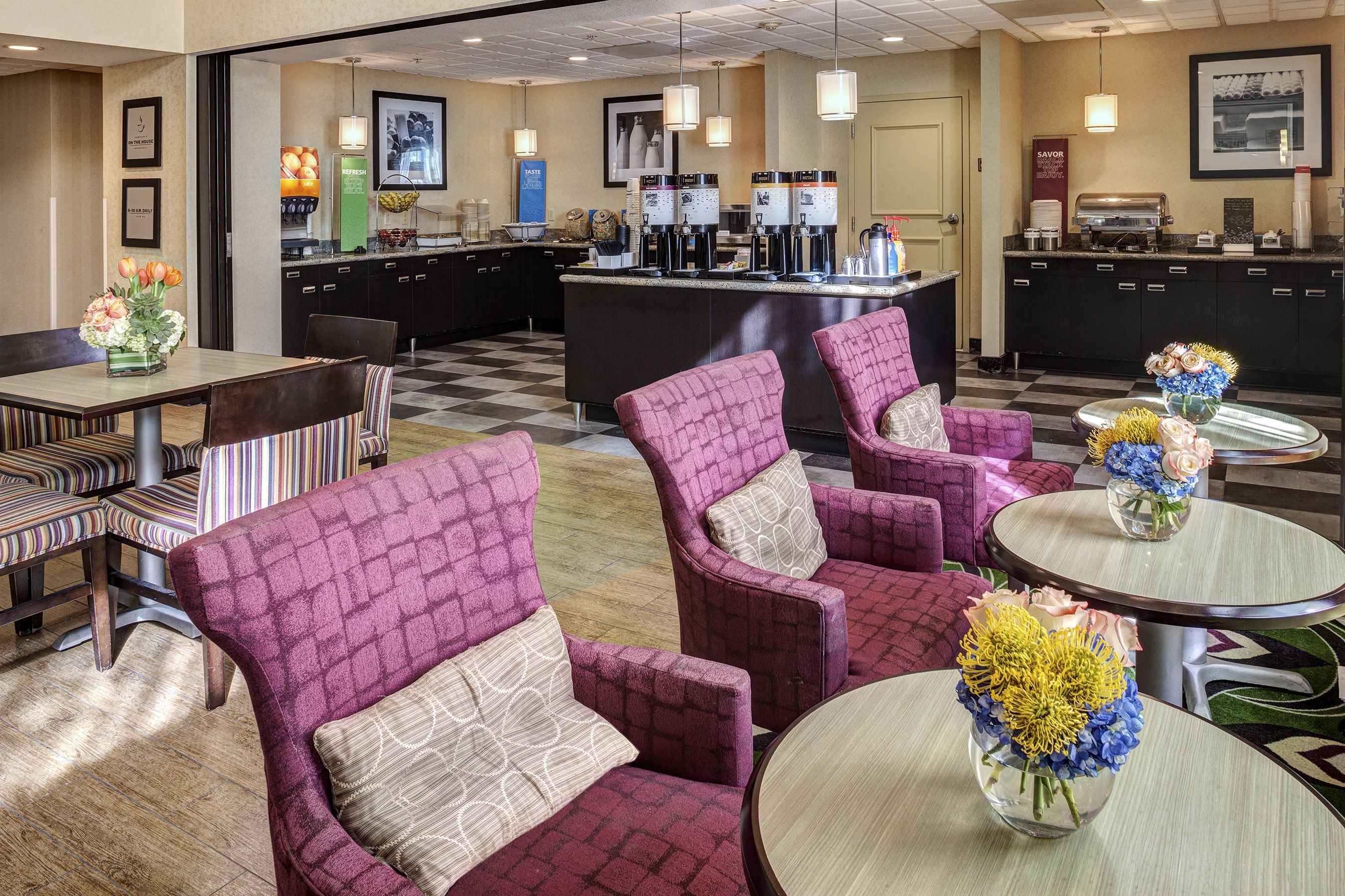 Een hotellobby met zithoeken, een koffieautomaat en een receptiebalie.