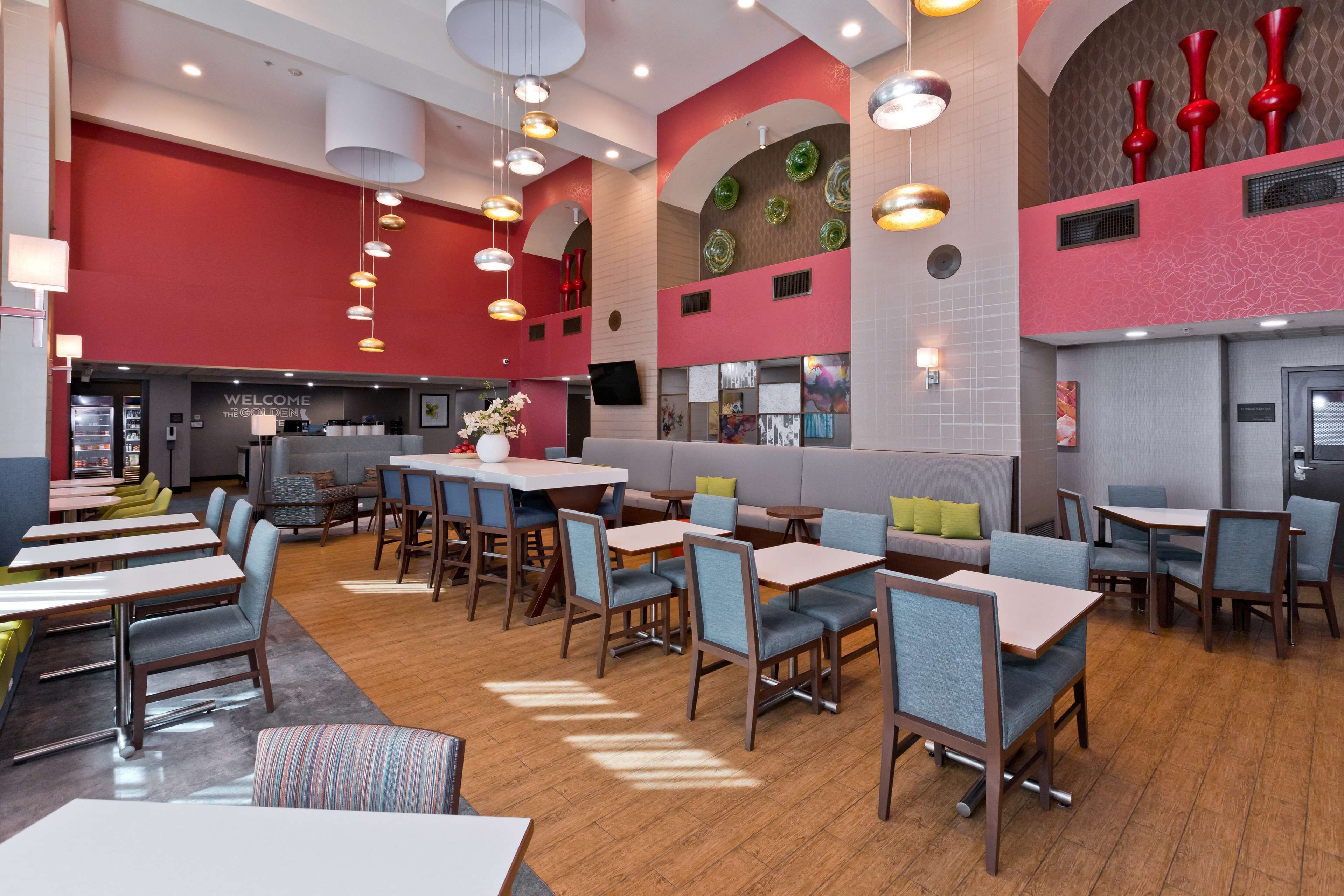 Un restaurant moderne doté de plusieurs espaces de restauration, notamment des banquettes et des tables, ainsi qu’un bar agrémenté d’une enseigne « Bienvenue ».