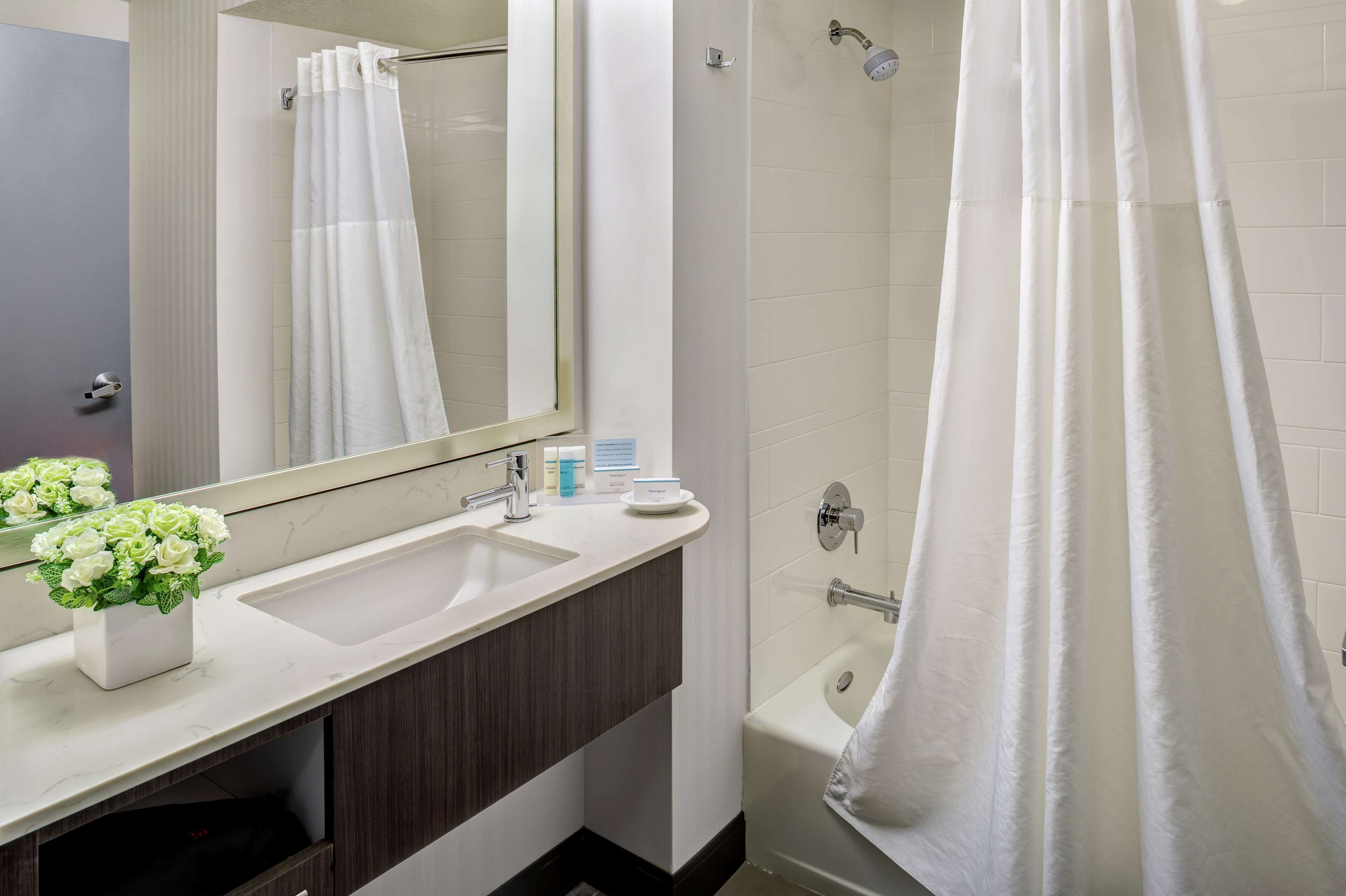 A modern bathroom with a white sink, mirror, and shower curtain.