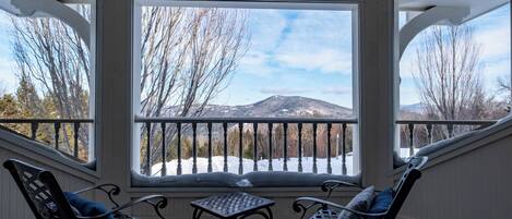 A covered outdoor seating area with a view of a snowy landscape and mountains.