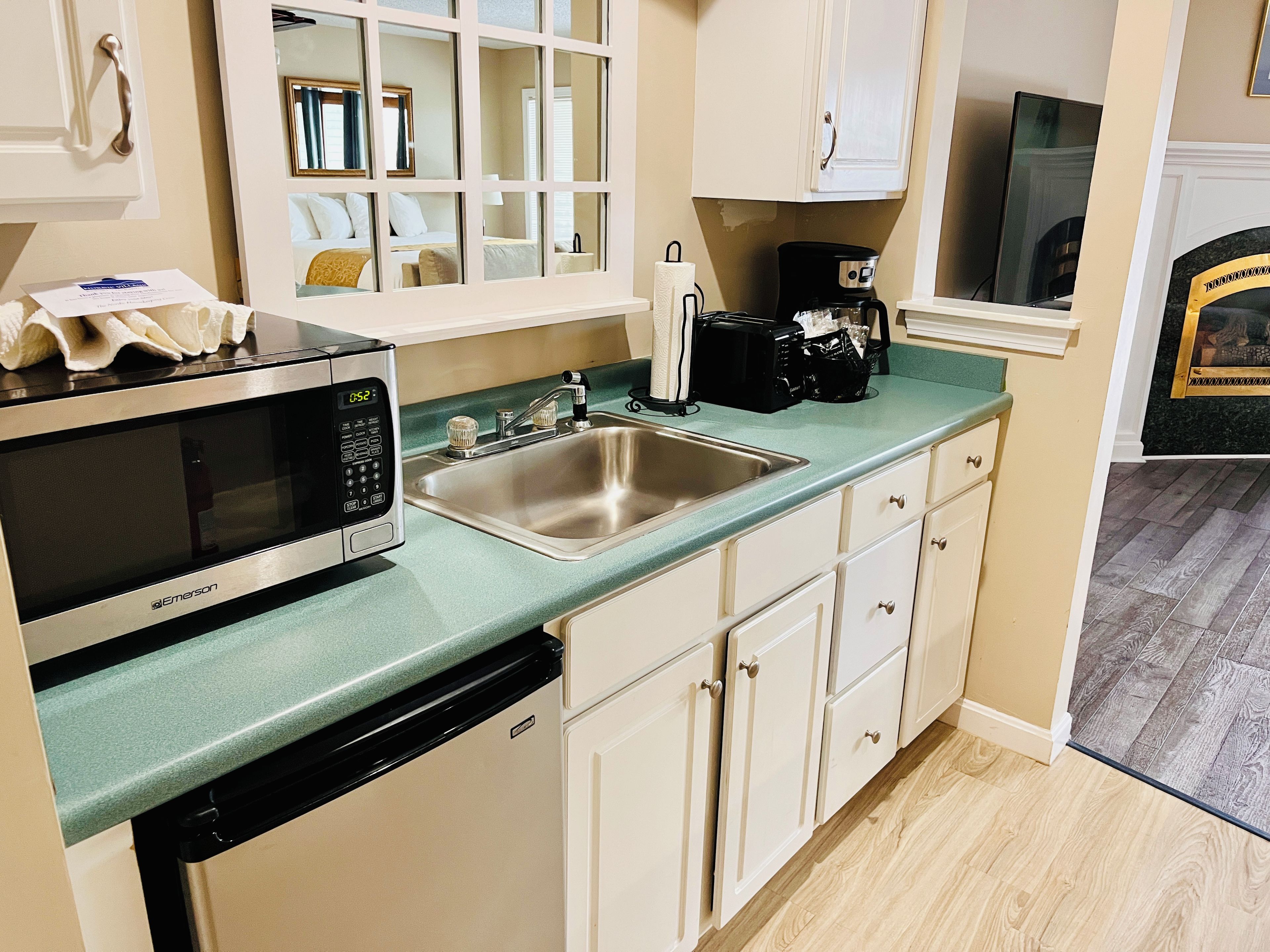 A compact kitchenette with a microwave, sink, and coffee maker.
