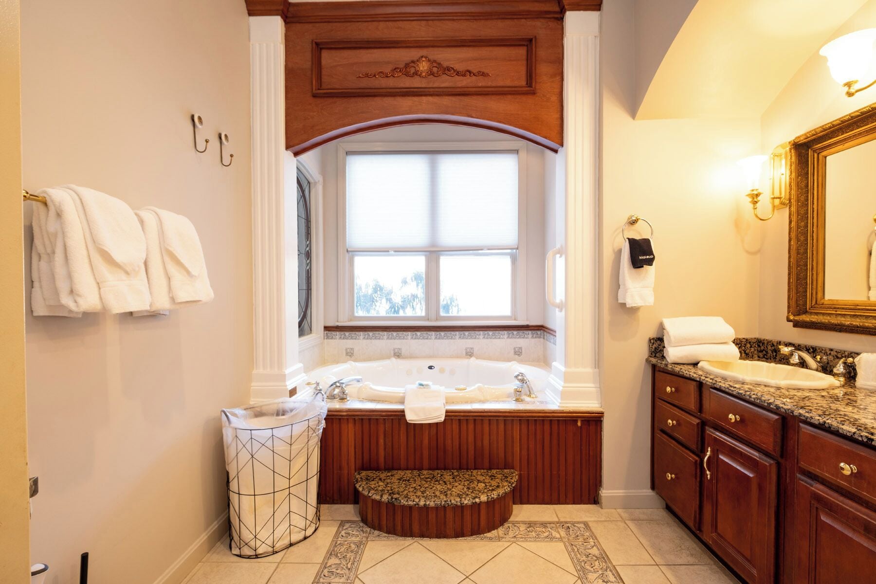 Une salle de bain dotée d’une grande fenêtre, d’une baignoire, d’un lavabo et de meubles en bois.