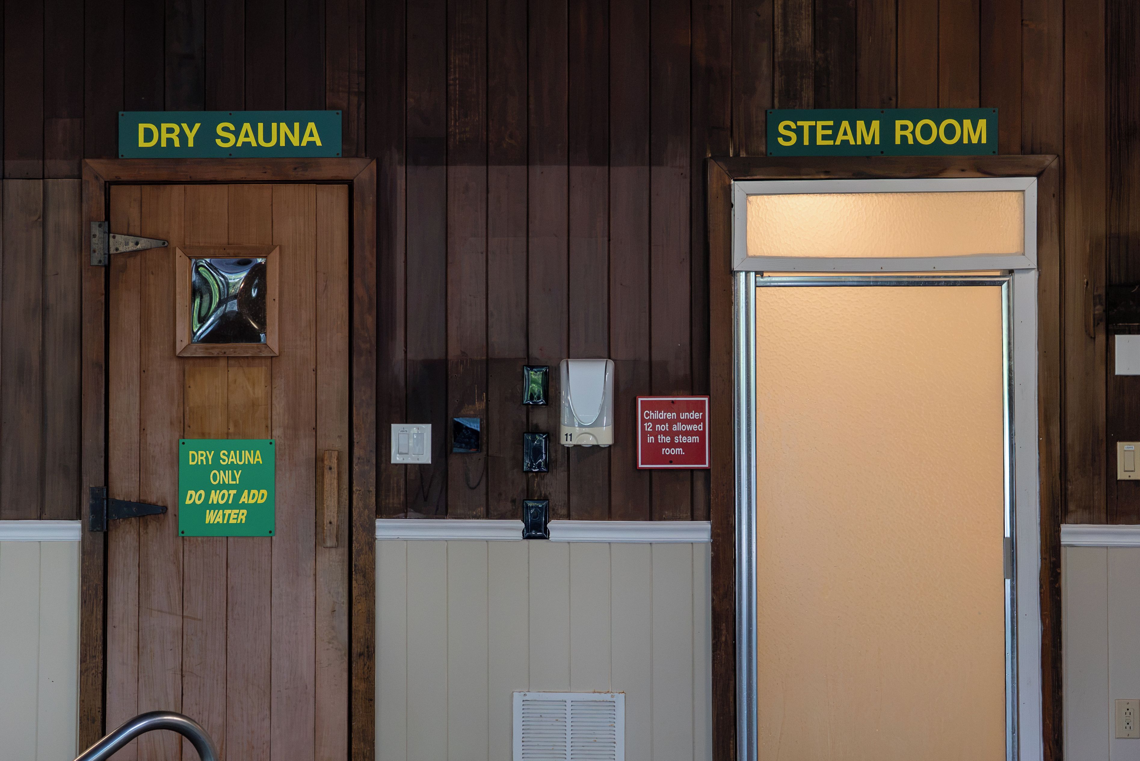 A dry sauna and steam room entrance with signs indicating usage rules.