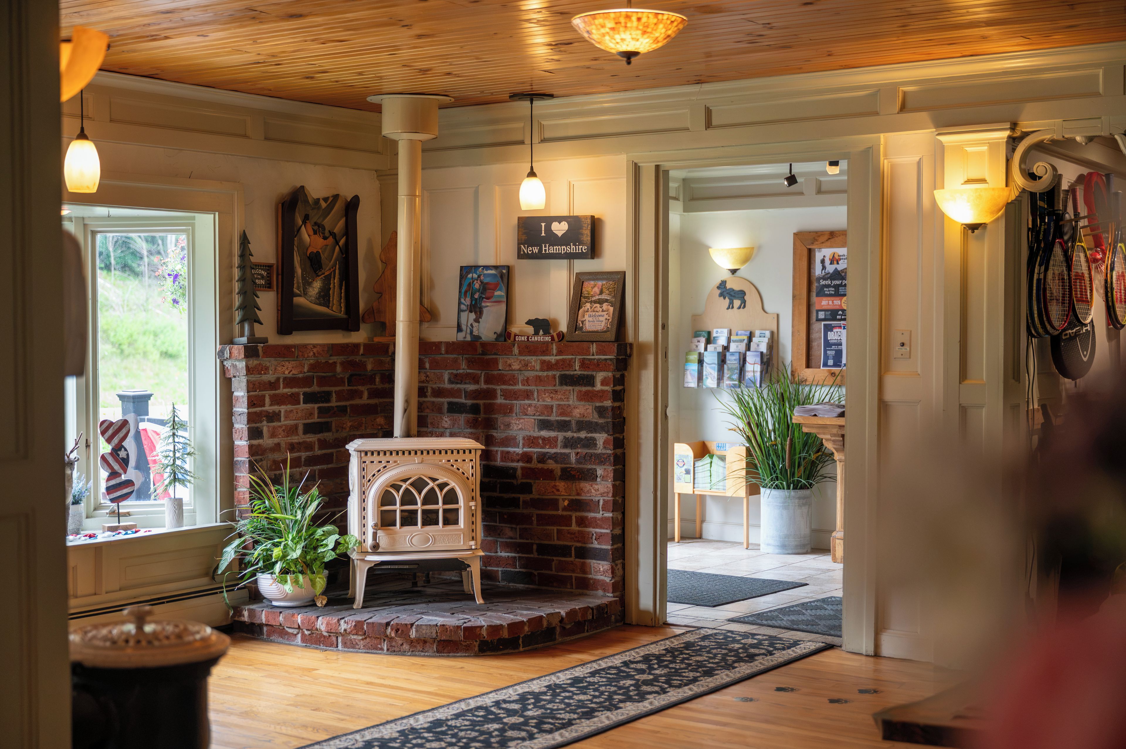 A cozy room with a brick fireplace, wooden ceiling, and a view of the outdoors.