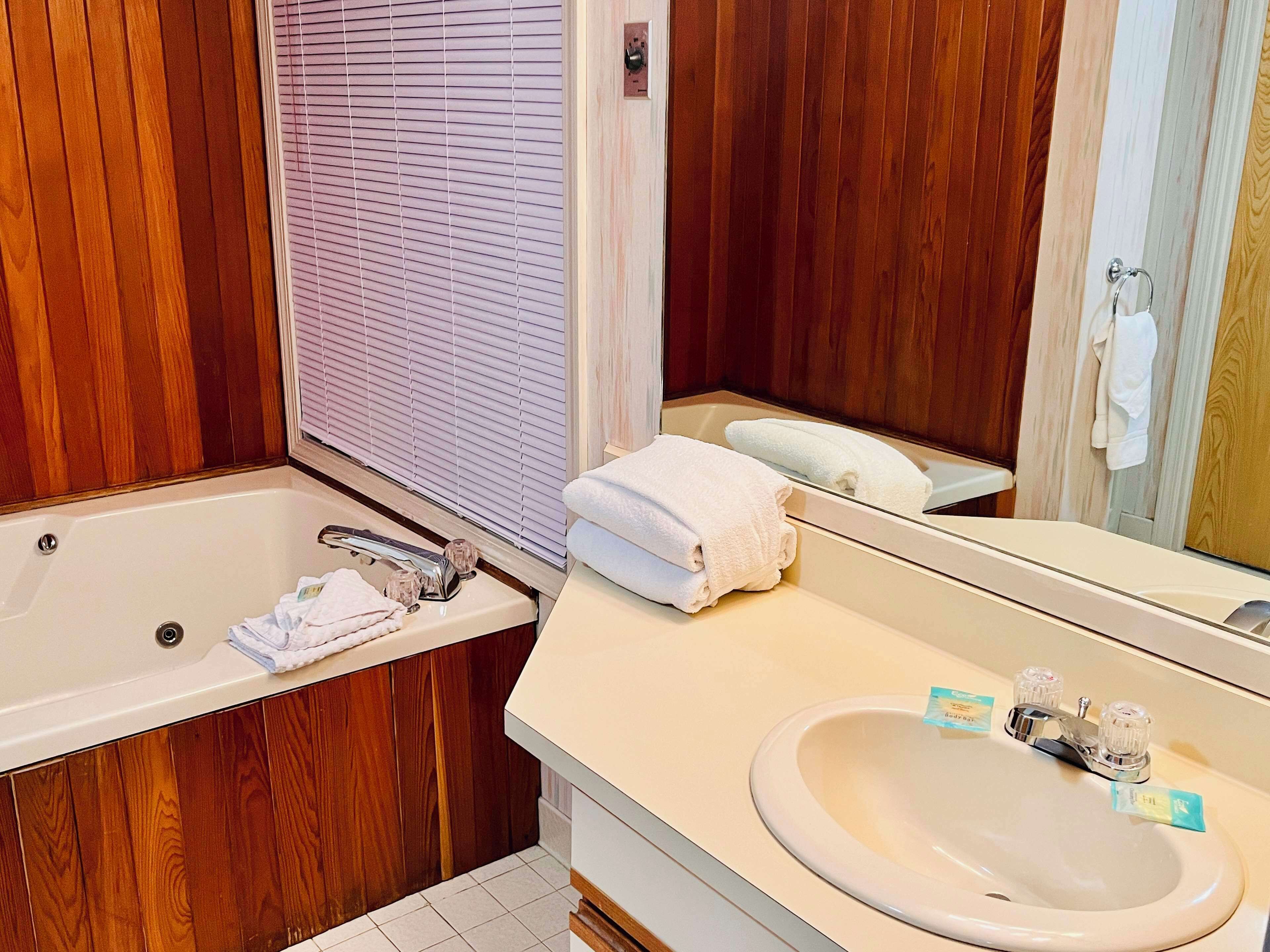 Een badkamer met een bad, een wastafel en een spiegel.
