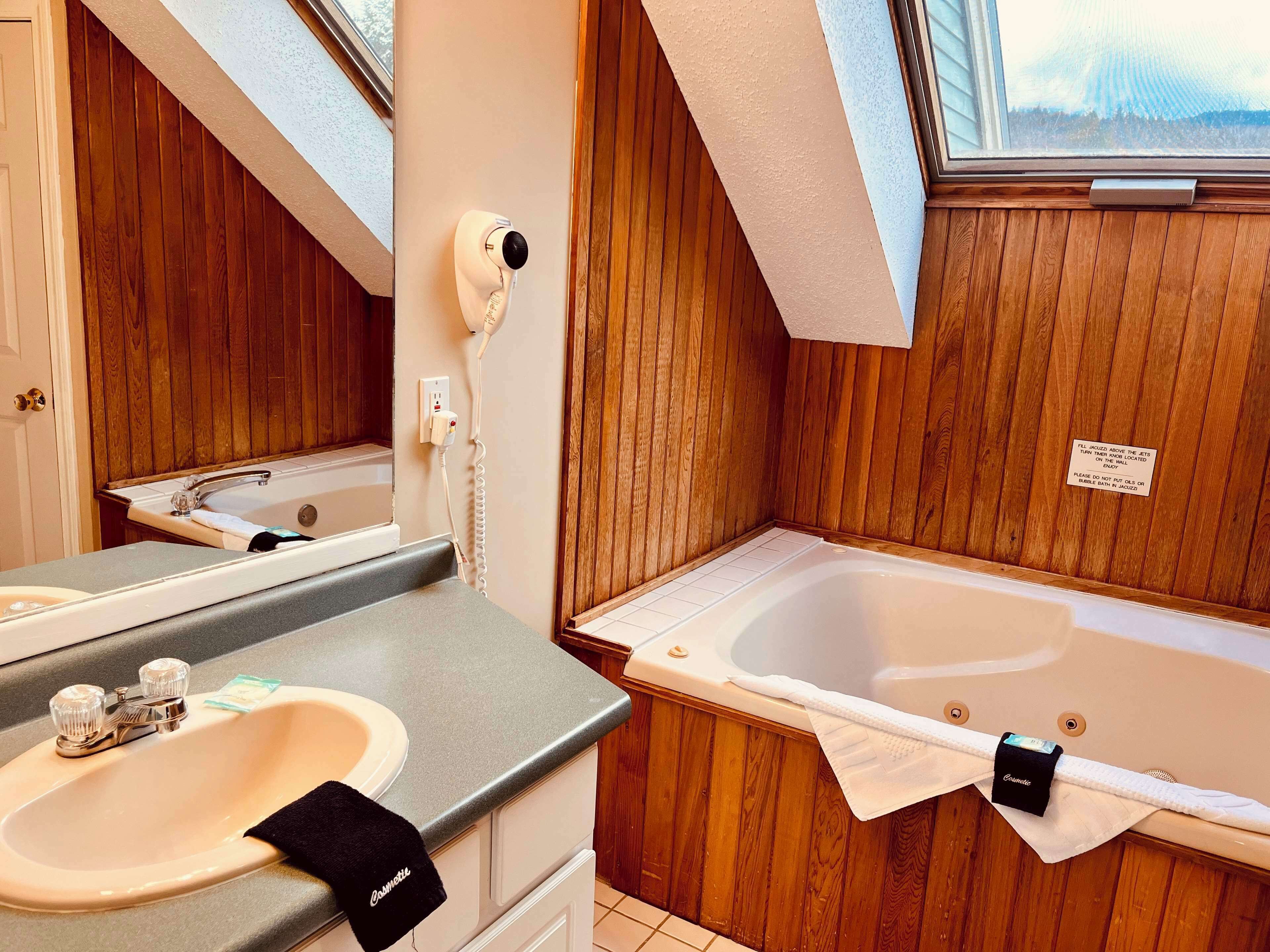 Une salle de bain avec un meuble-lavabo en bois, un évier, un miroir et une baignoire.