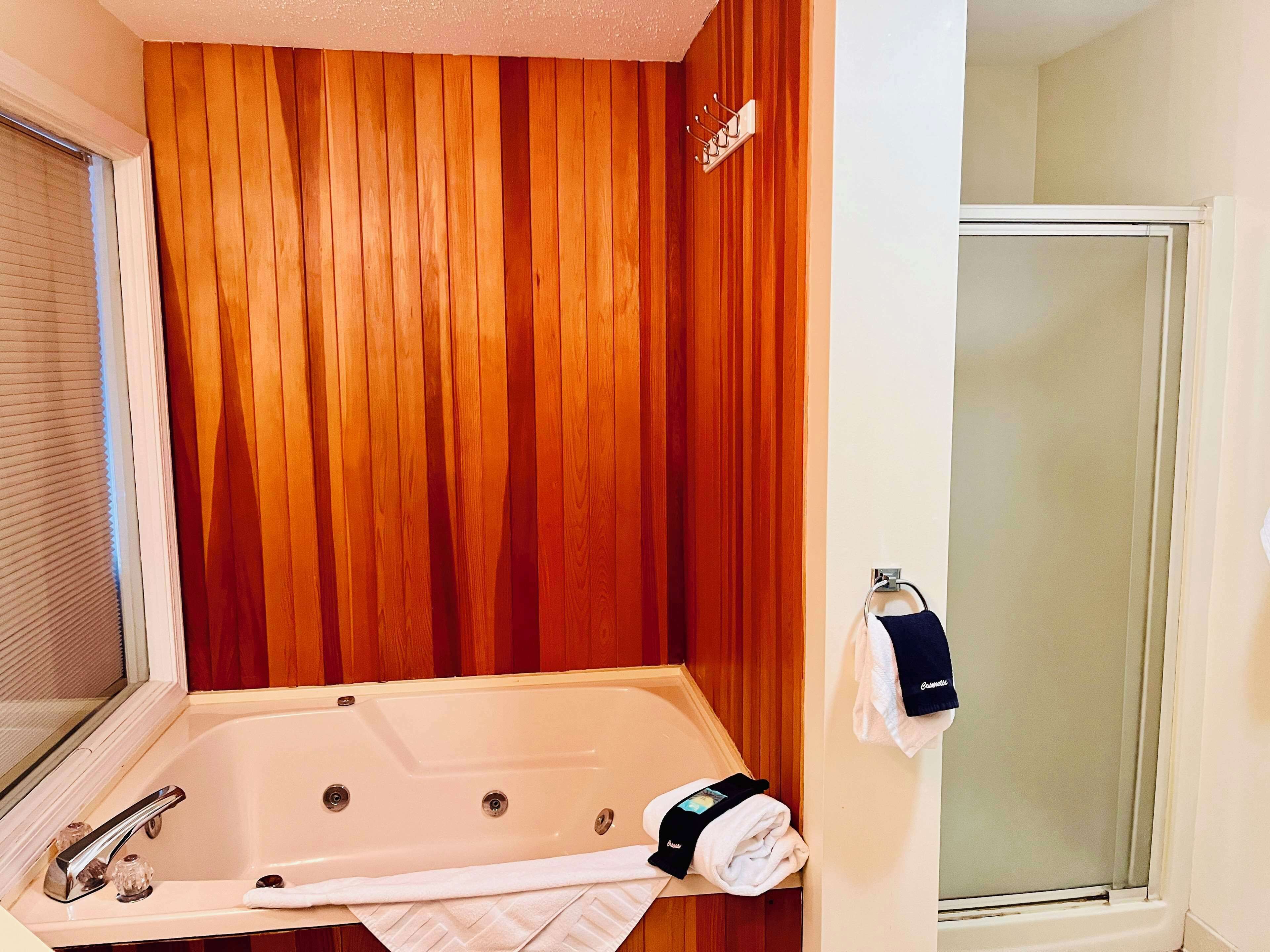 Un baño con pared de paneles de madera, una bañera, toallero y zona de ducha.