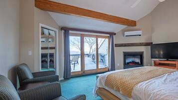 Habitación de hotel con cama, televisor, chimenea y puerta corrediza de vidrio que da a un balcón.