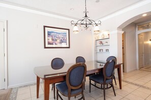 A dining area with a wooden table and chairs, a chandelier, a framed picture on the wall, and a hallway with shelves. - Nordic Village Resort (Jackson)