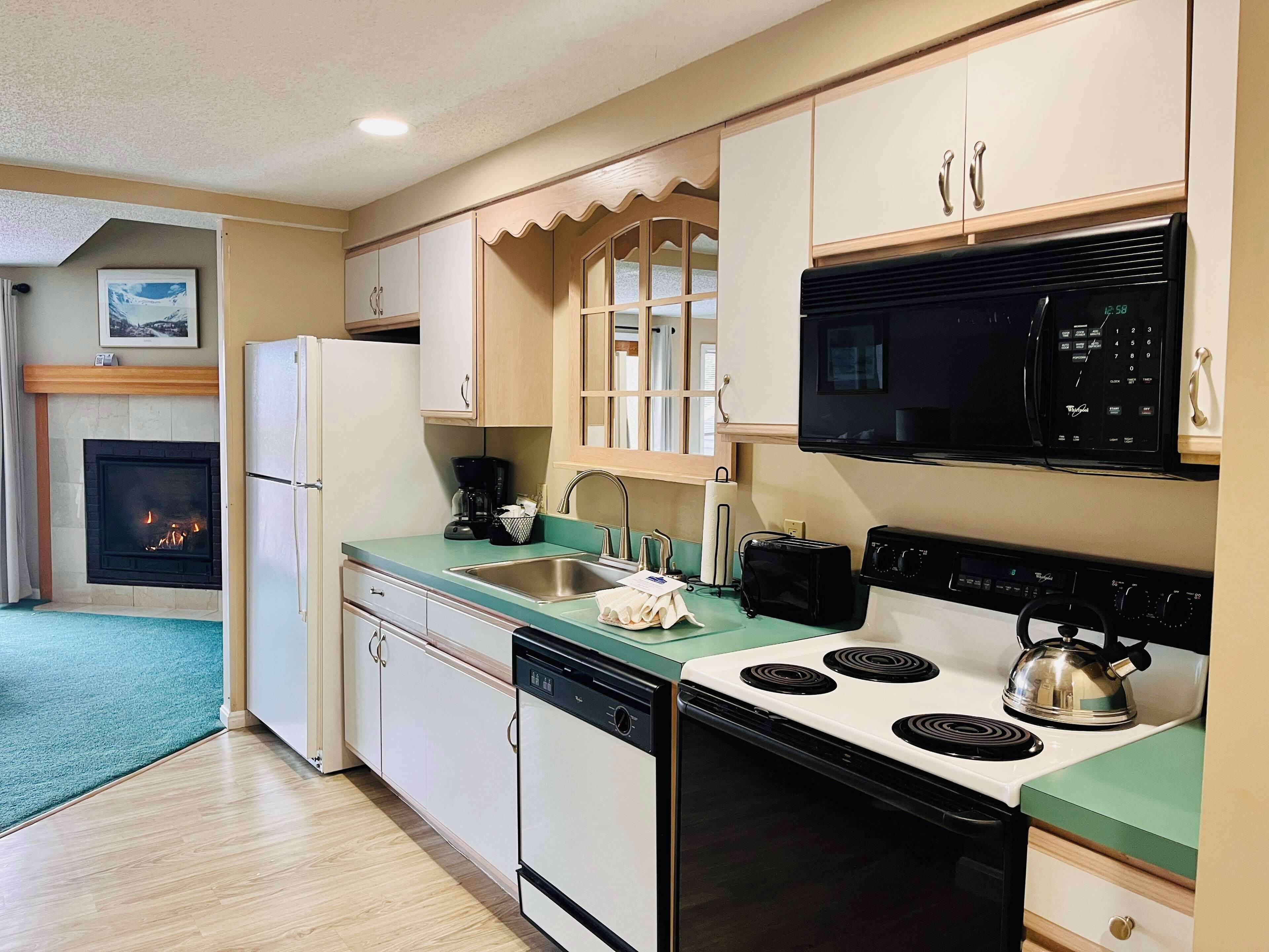 A compact kitchen with a microwave, toaster, stove, and dishwasher.