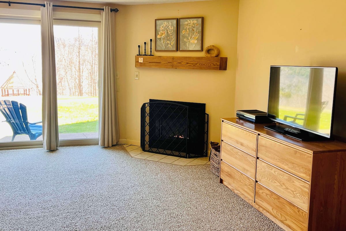 A living room with a fireplace, a television, and a sliding glass door leading to an outdoor area.