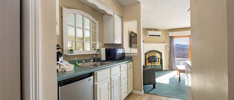 A kitchen with a dishwasher, microwave, and a view of a fireplace and balcony.