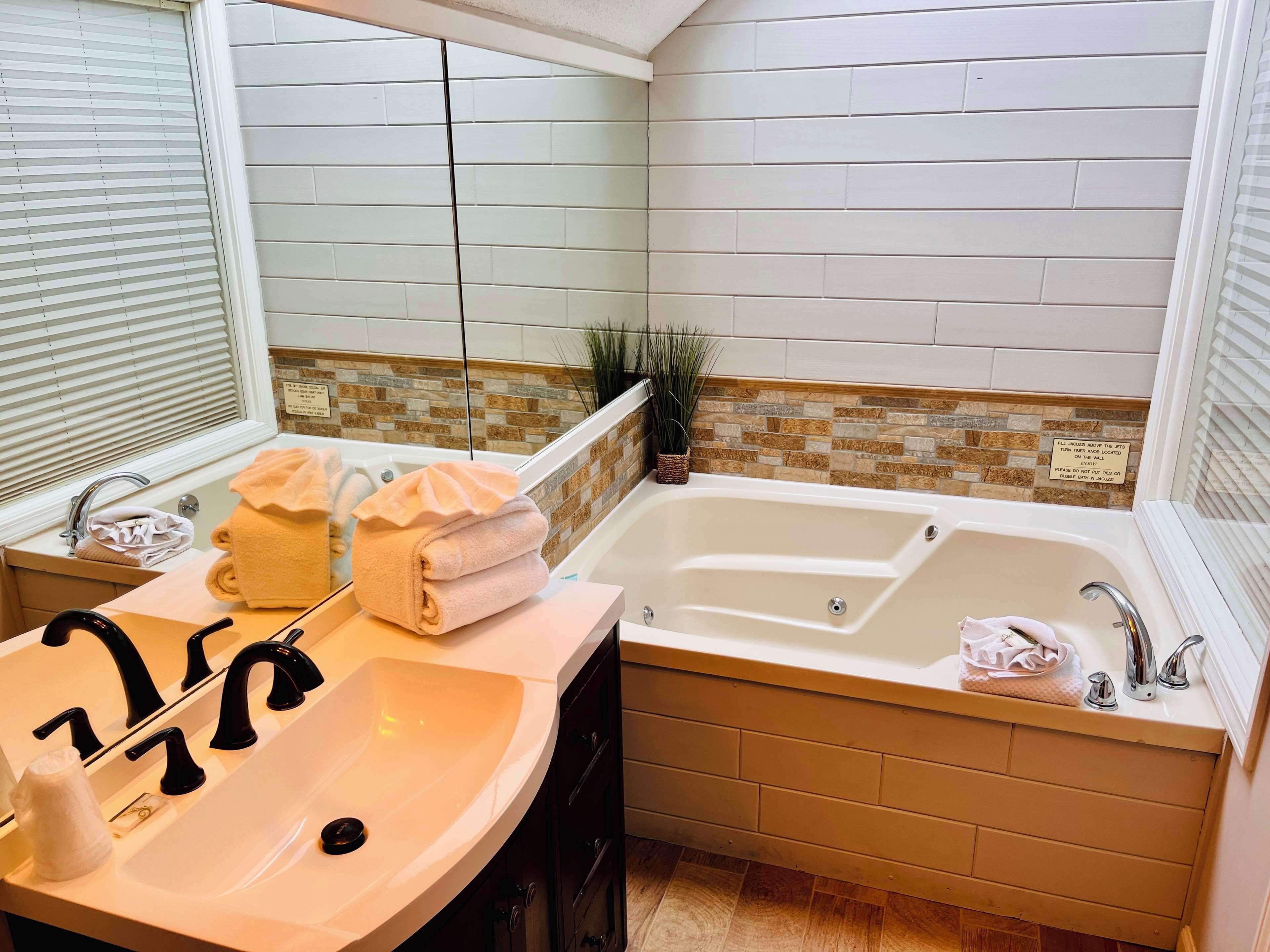 A bathroom with a sink, two faucets, a bathtub, and a mirror.