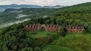 A cluster of brick buildings with multiple floors, surrounded by lush greenery and hills in the background. - Nordic Village Resort (Jackson)