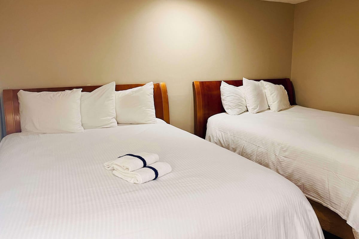 Two single beds with wooden headboards and white bedding, a folded towel, and a ceiling light.