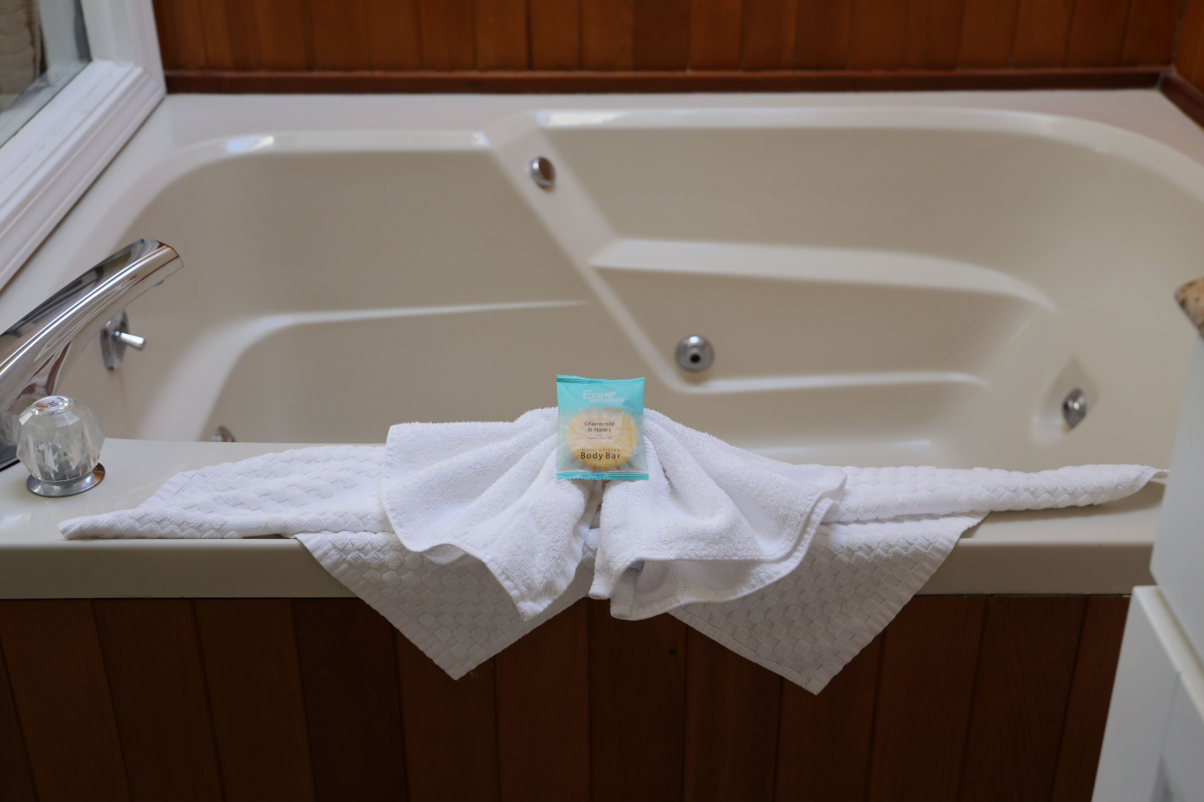 Una bañera con una toalla blanca y un paquete de jabón corporal.