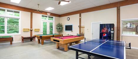 Une salle de loisirs équipée d’une table de billard, d’une table de ping-pong et d’une table de jeu de fléchettes.