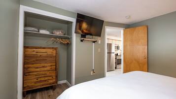 A bedroom with a wooden dresser, a bed, and a TV mounted on the wall.