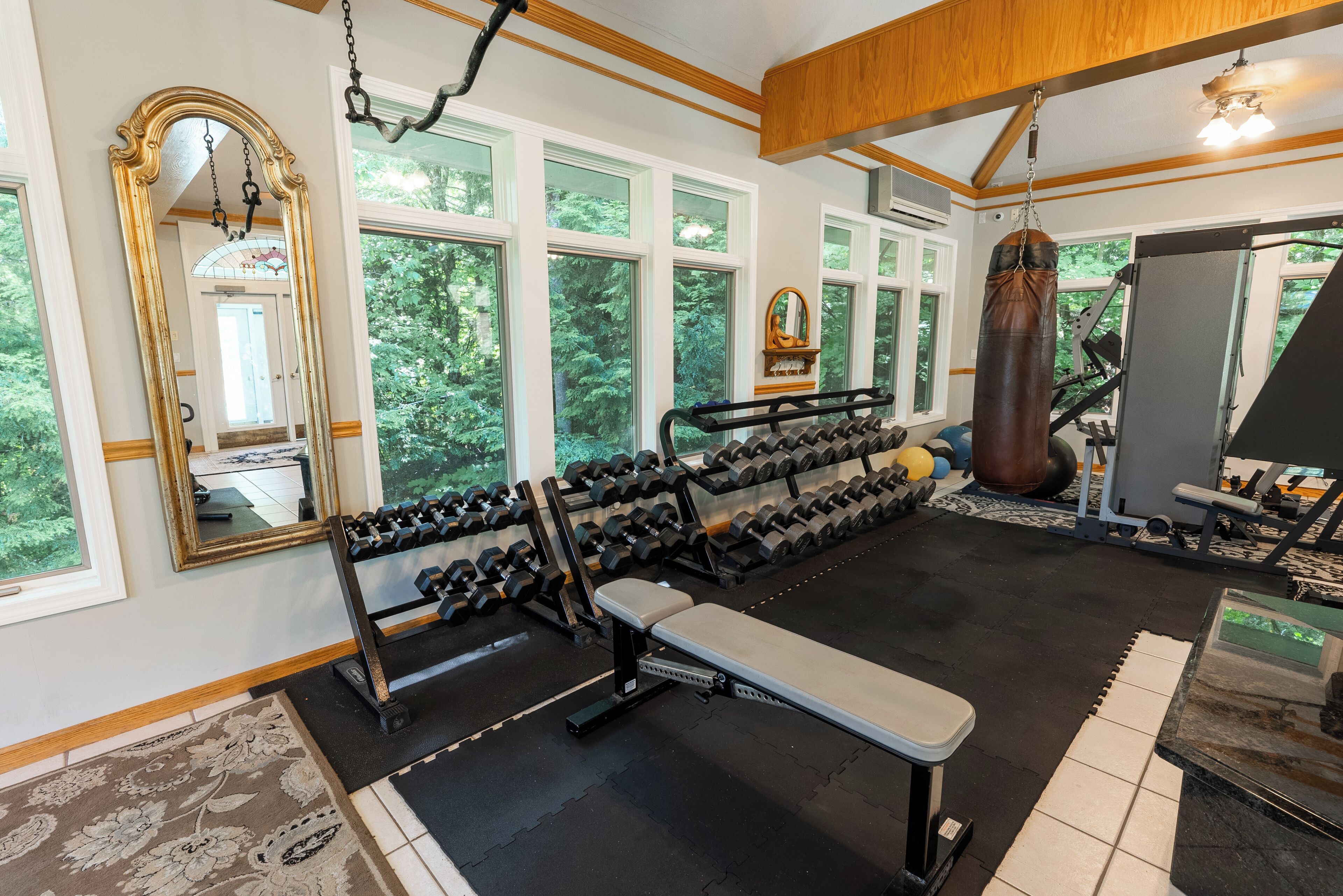 A gym with exercise equipment, large windows, and a mirror.