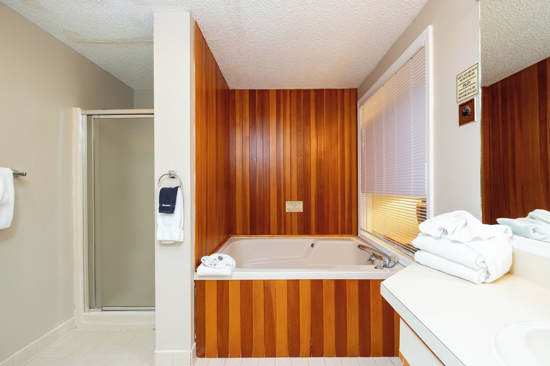 Un baño con pared de paneles de madera, una bañera y un lavamanos con espejo.