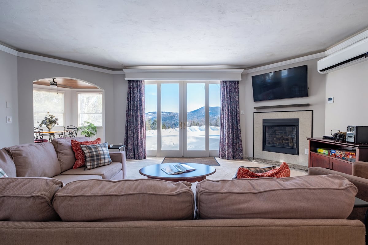 A living room with a sofa, a coffee table, a fireplace, and a TV.