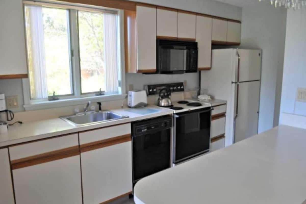 A kitchen with white cabinets, a microwave, a stove, a dishwasher, and a refrigerator.
