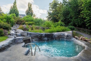 Un área de aguas termales con una piscina, rodeada de rocas y vegetación.
