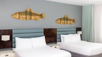 A hotel room with two beds, a wooden headboard, and two wall-mounted fish decorations.