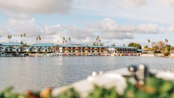 Un hotel frente al mar con varias construcciones, un puerto deportivo y palmeras.