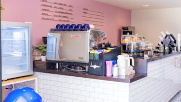 Un café con una máquina de espresso La Cimbali, un menú en la pared y diferentes recipientes para café.
