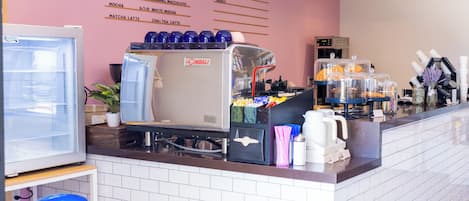 A coffee bar with a La Cimbali espresso machine, a menu on the wall, and a variety of coffee containers.