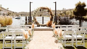 A wedding aisle with white chairs and floral decorations leading to a decorated arch.