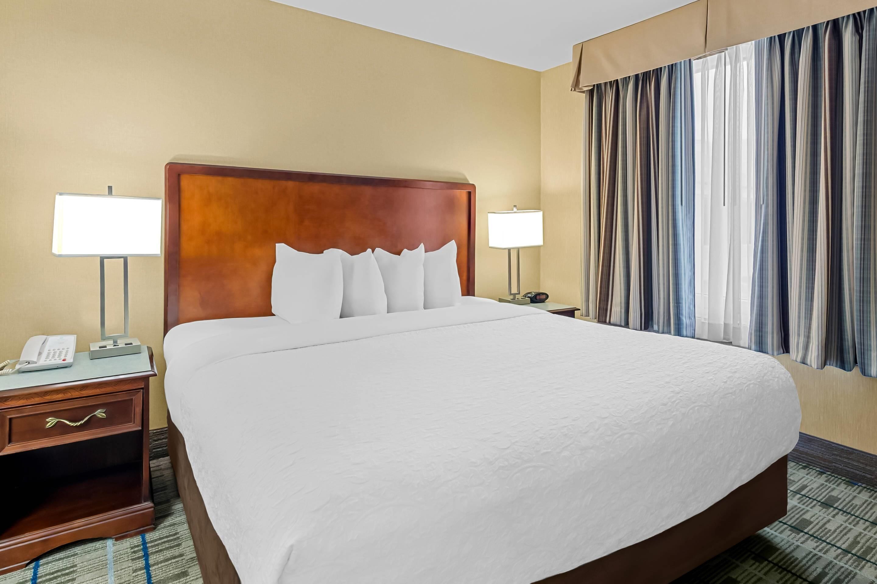 A hotel room with a large bed, two bedside lamps, a telephone, and a nightstand.