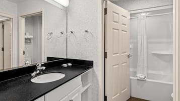 A modern bathroom with a black countertop sink, white cabinets, and a glass shower enclosure.