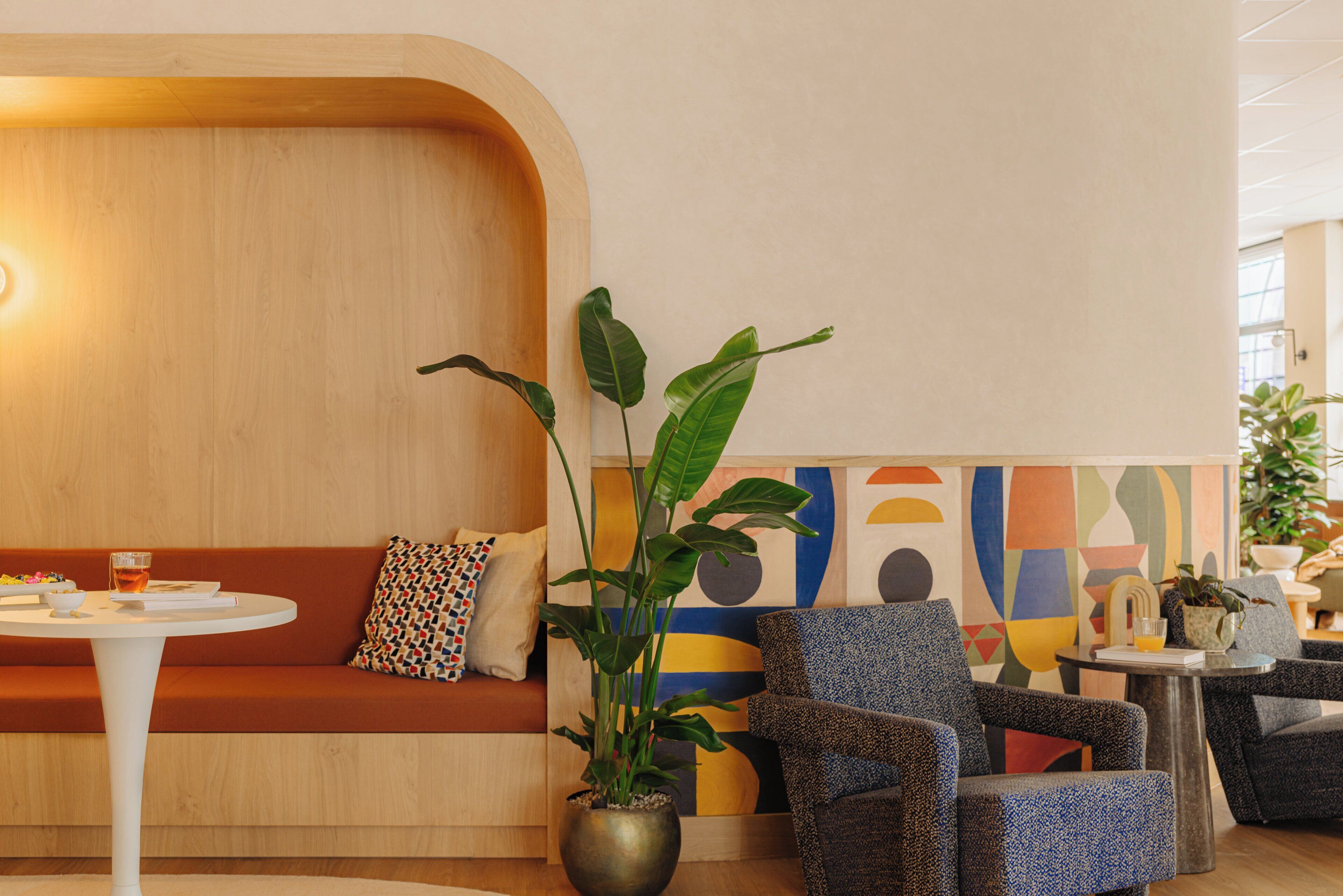 Un área de estar moderna con un banco de madera, una mesa redonda y una planta en maceta.