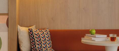 A modern room with a wooden accent wall, a round white table, a cushioned bench, and a small stool.
