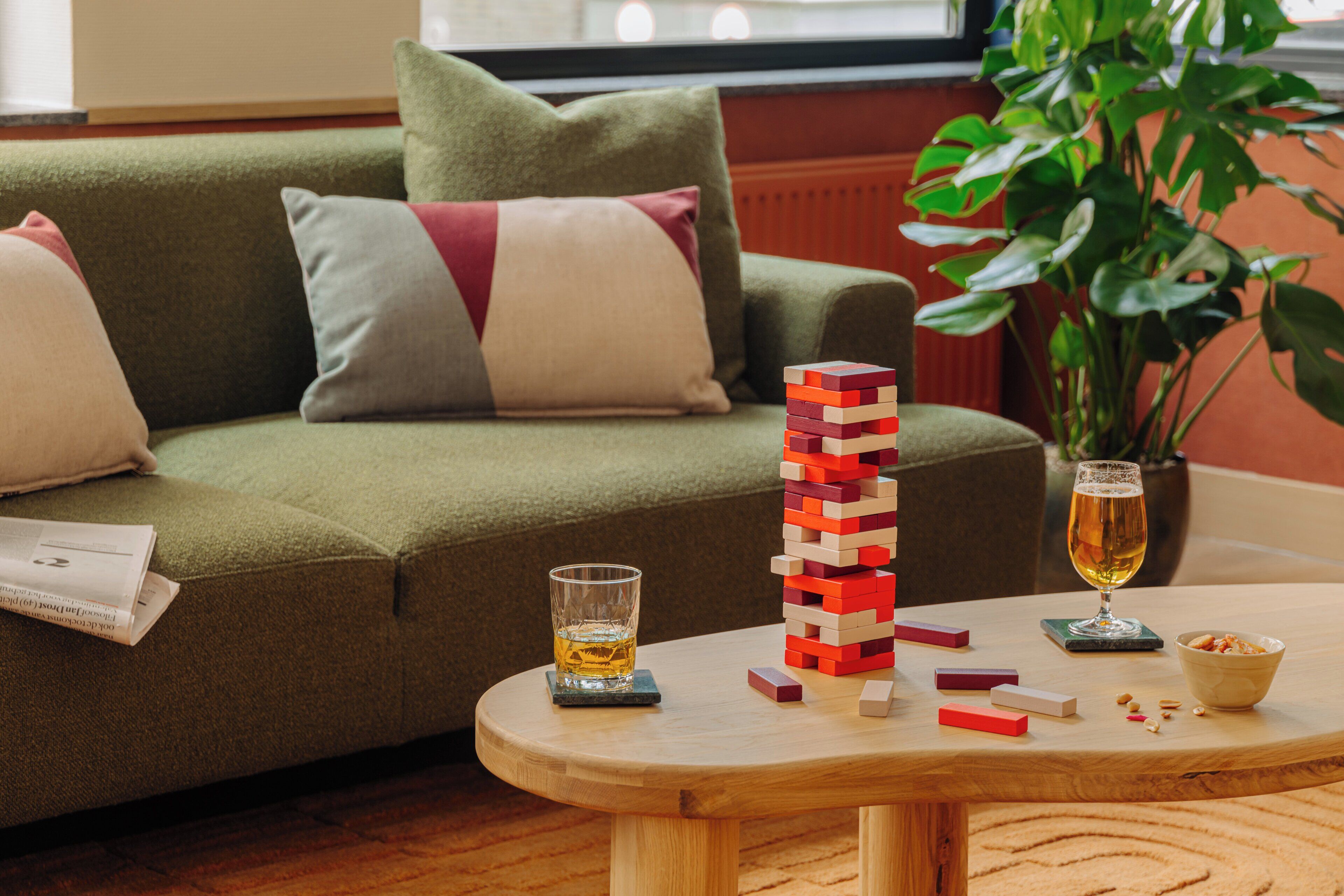 Una sala de estar con un sofá verde, una mesa de centro de madera, una cerveza en un vaso y una planta.